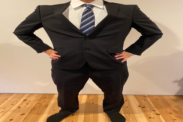 スーツで腰に手を当てている画像
